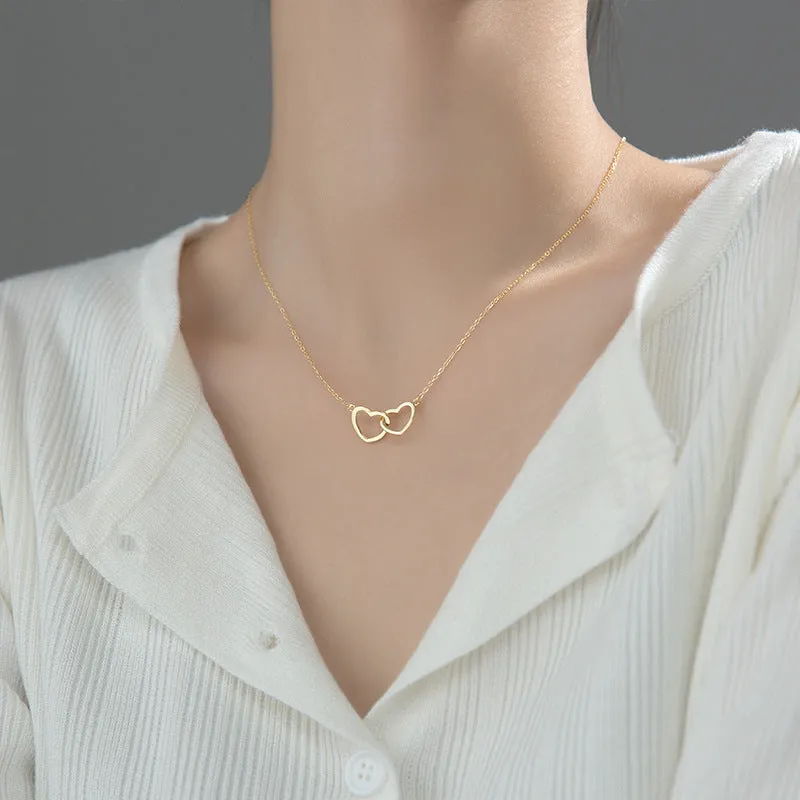 Double heart interlocking titanium steel necklace in gold on a white background with cross chain substyle