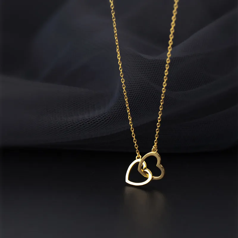 Double heart interlocking titanium steel necklace in gold on a white background with cross chain substyle