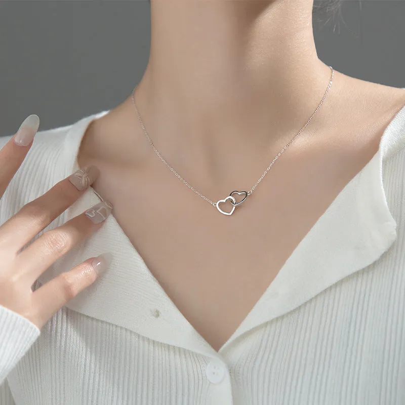 Double heart interlocking titanium steel necklace in gold on a white background with cross chain substyle