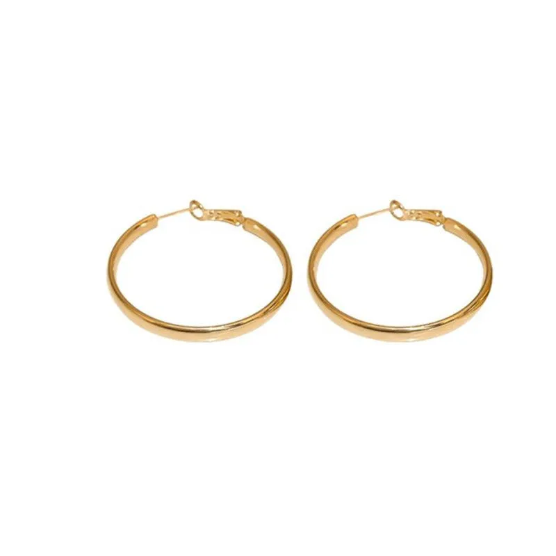 A pair of large, circular gold metal earrings against a plain background.