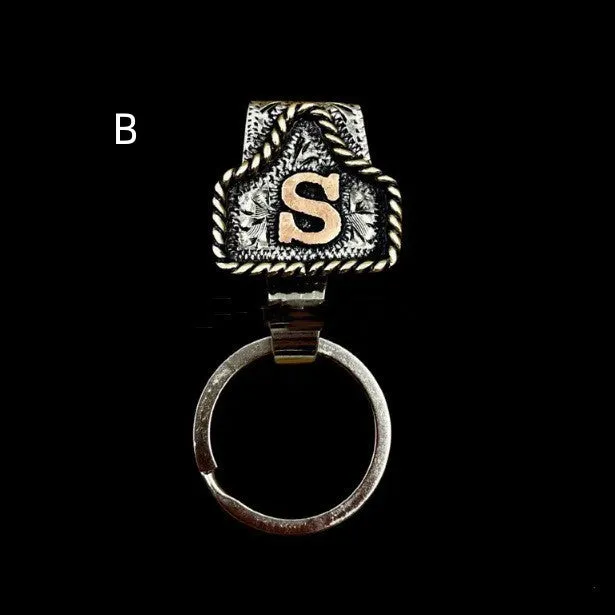 Handmade cow tag shaped metal keychain with a brown leather attachment strap.
