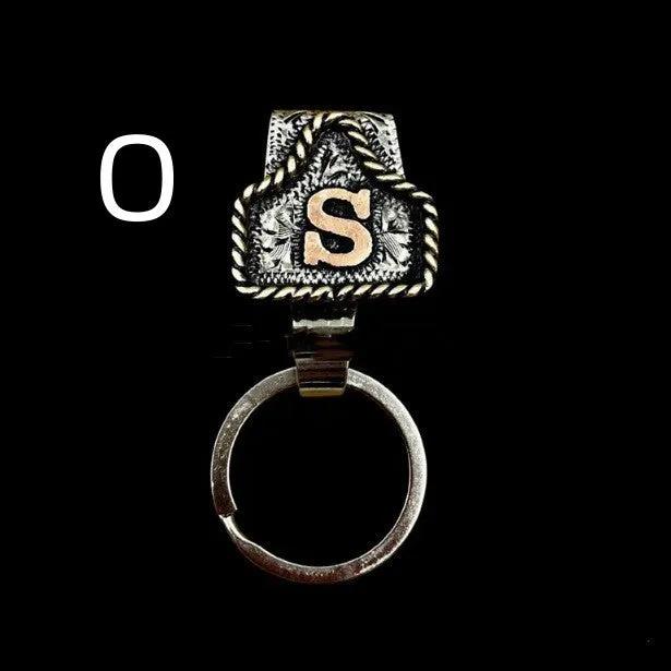 Handmade cow tag shaped metal keychain with a brown leather attachment strap.