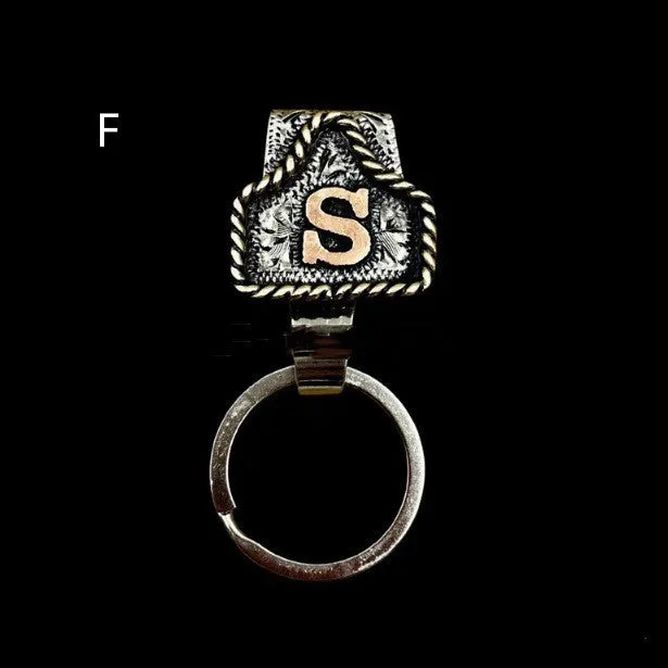 Handmade cow tag shaped metal keychain with a brown leather attachment strap.