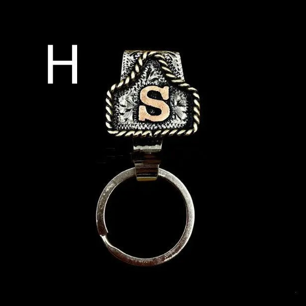 Handmade cow tag shaped metal keychain with a brown leather attachment strap.
