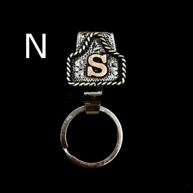 Handmade cow tag shaped metal keychain with a brown leather attachment strap.