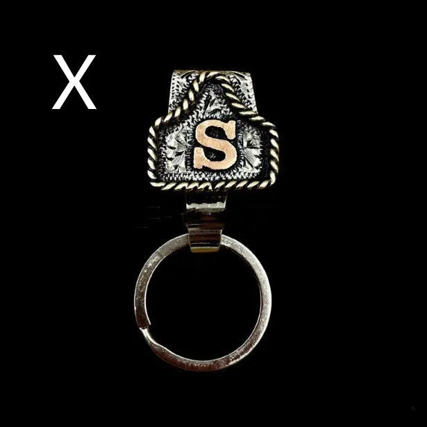 Handmade cow tag shaped metal keychain with a brown leather attachment strap.