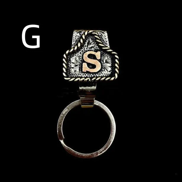 Handmade cow tag shaped metal keychain with a brown leather attachment strap.