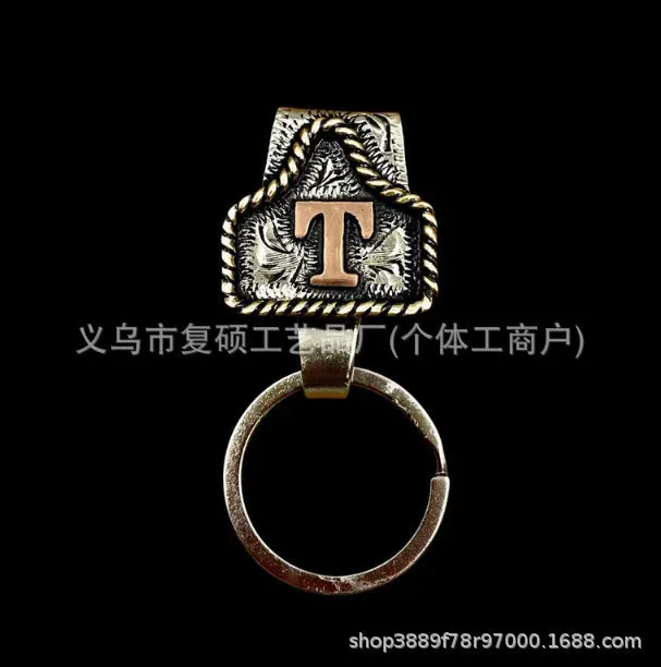 Handmade cow tag shaped metal keychain with a brown leather attachment strap.