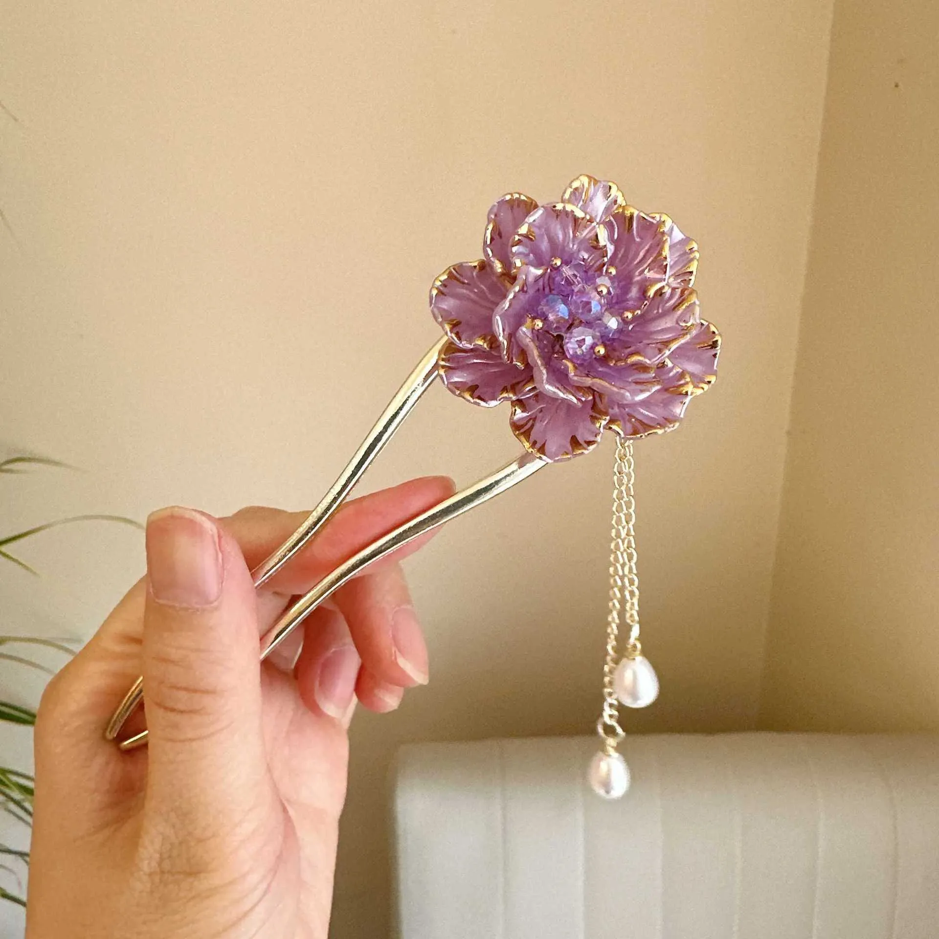 Close-up of a purple alloy U-shaped hairpin with a detailed peony flower and tassel design on a white background.