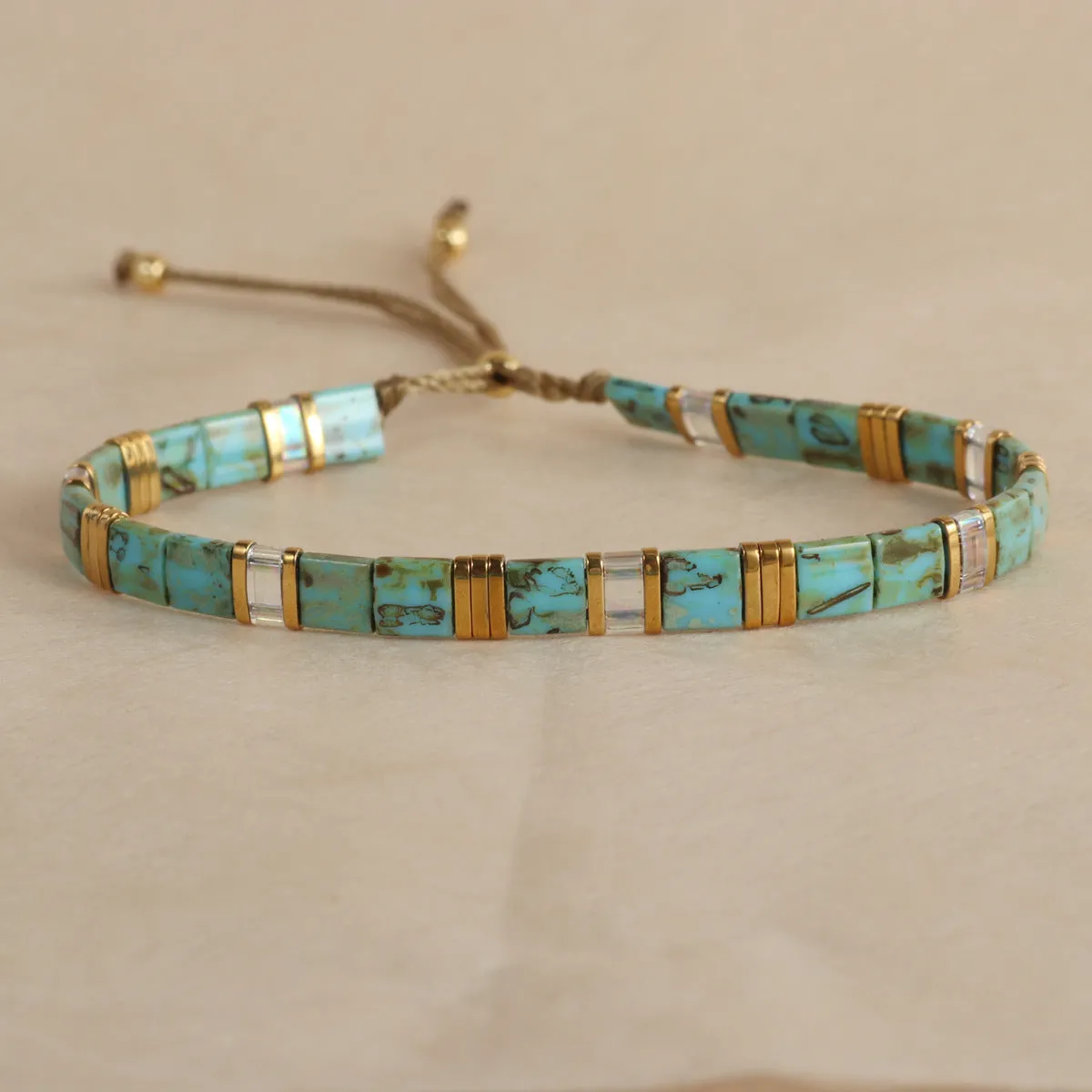 Geometric round glass bead bracelet in five colour options on a wrist.