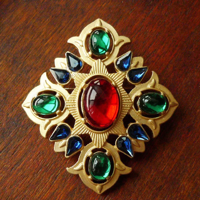 A selection of eight different zinc alloy retro baroque brooches in a diamond shape on a fabric background.