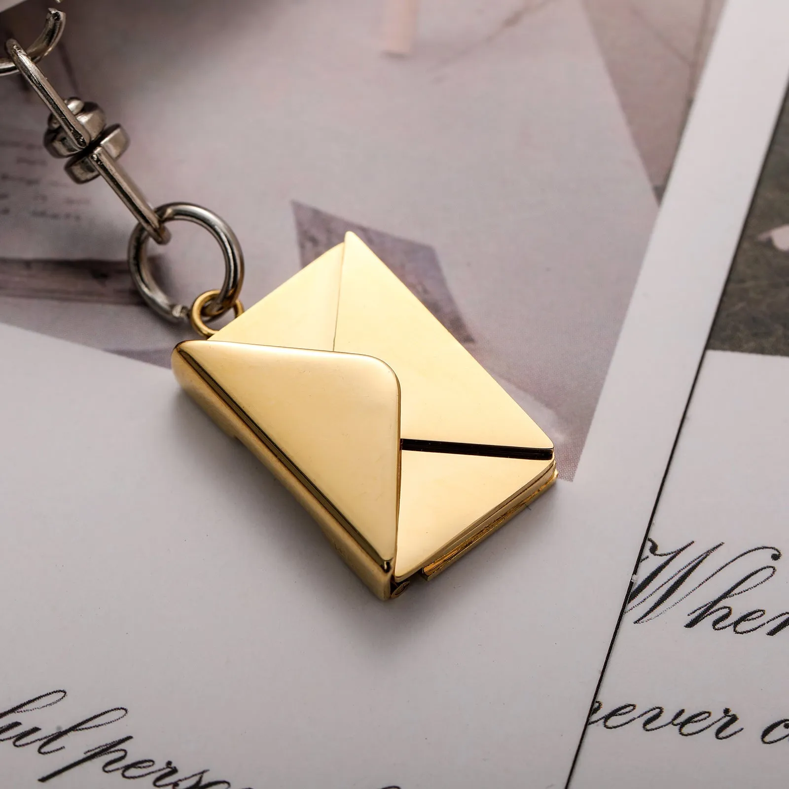 Stainless steel keychain with engraved card inside in gold and silver envelope finish on neutral background
