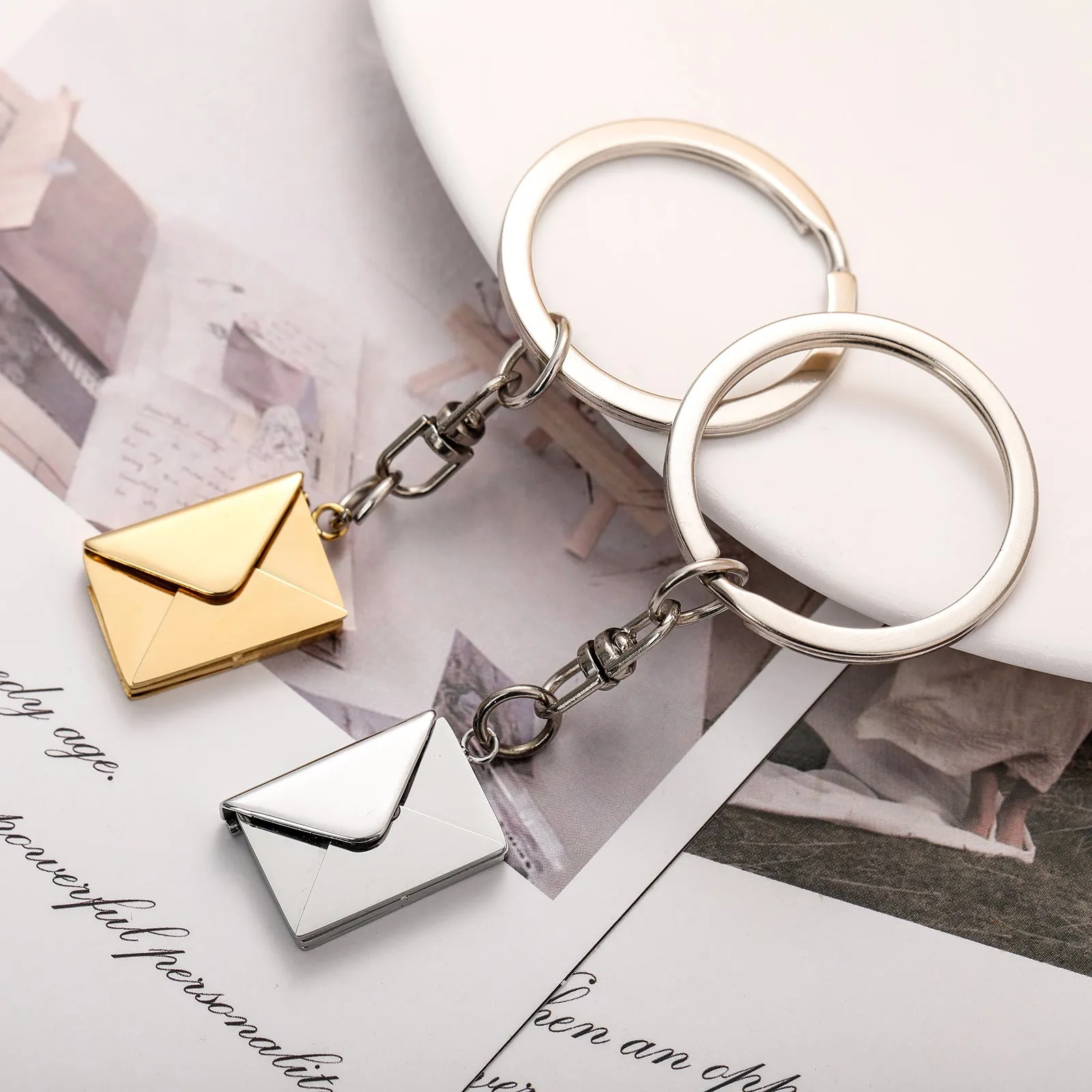 Stainless steel keychain with engraved card inside in gold and silver envelope finish on neutral background