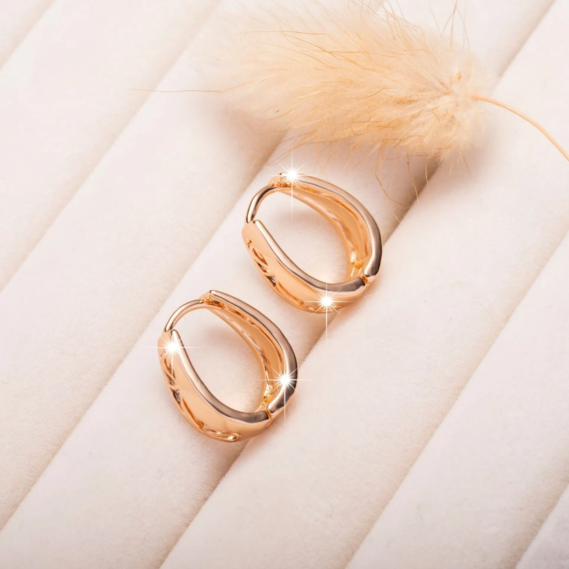 Rose gold hollow carved U-shaped copper earrings on light background