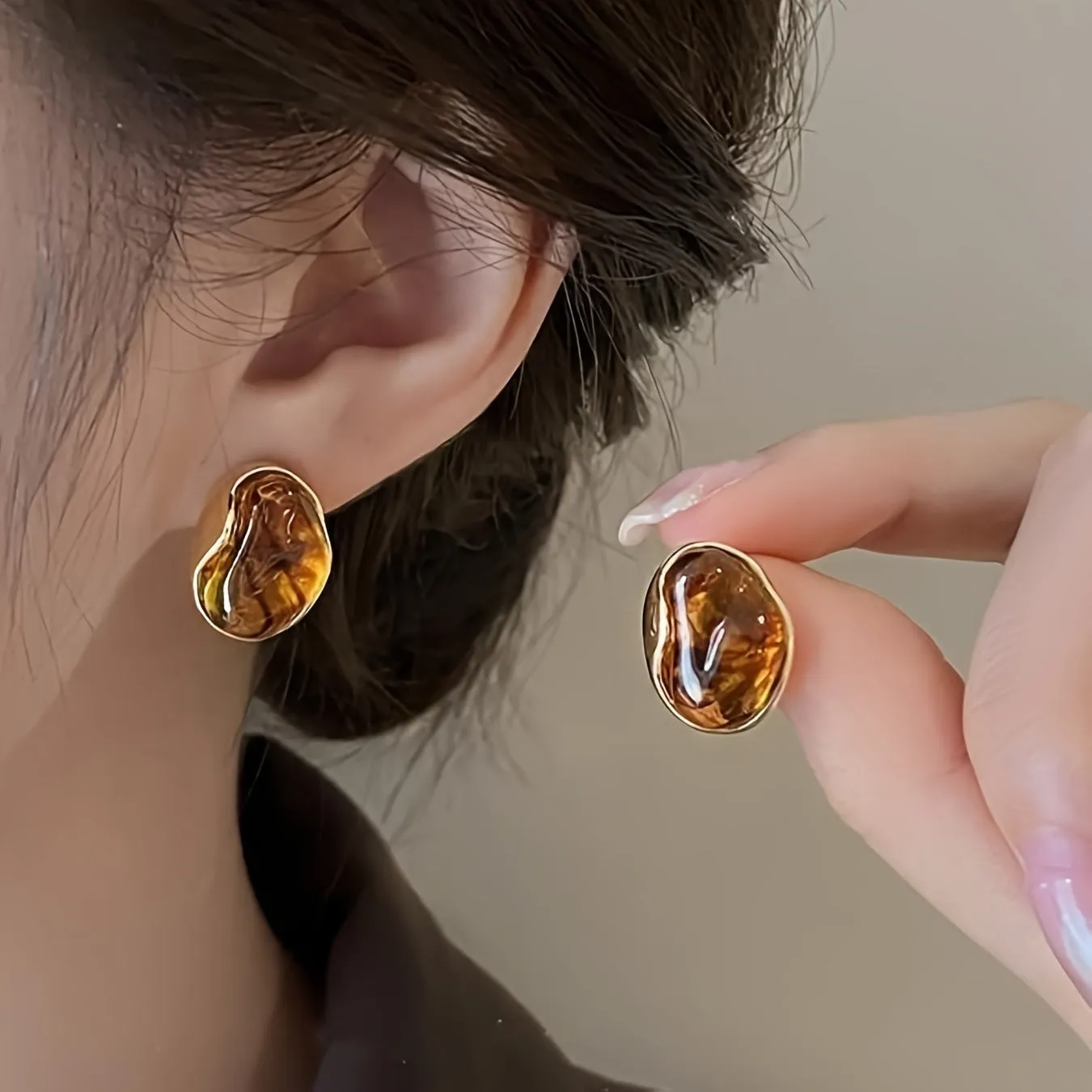 Three pairs of geometric tassel earrings in Maillard, amber, and tigereye colours on a white background