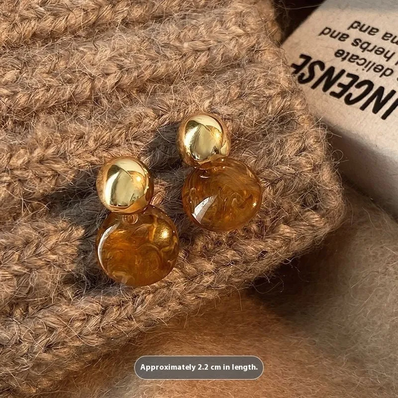 Three pairs of geometric tassel earrings in Maillard, amber, and tigereye colours on a white background