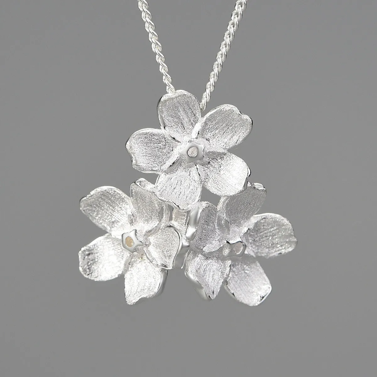 Myosotis Sylvatica forget-me-not flower sterling silver pendant in pastoral style on a plain background.