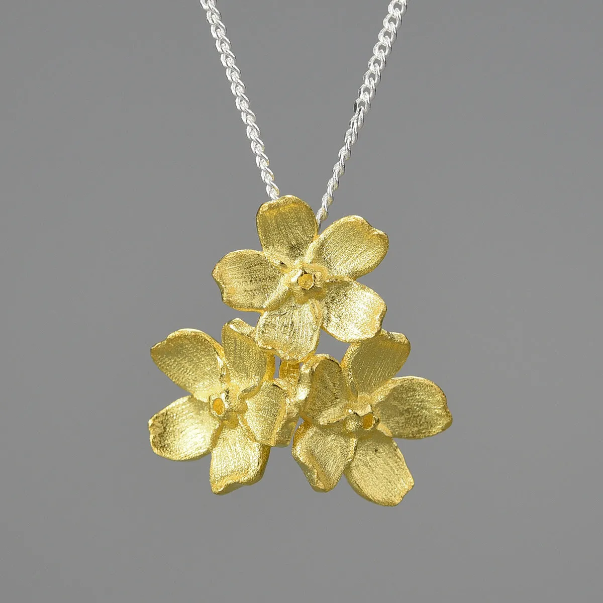 Myosotis Sylvatica forget-me-not flower sterling silver pendant in pastoral style on a plain background.