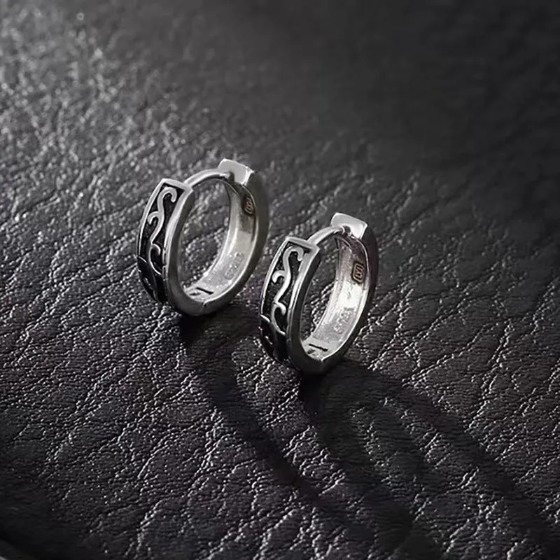 Close-up of a pair of men's geometric copper hip hop earrings on a dark background.