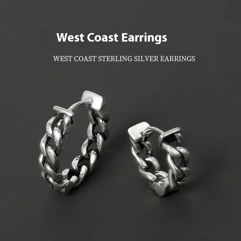 Close-up of a pair of men's geometric copper hip hop earrings on a dark background.