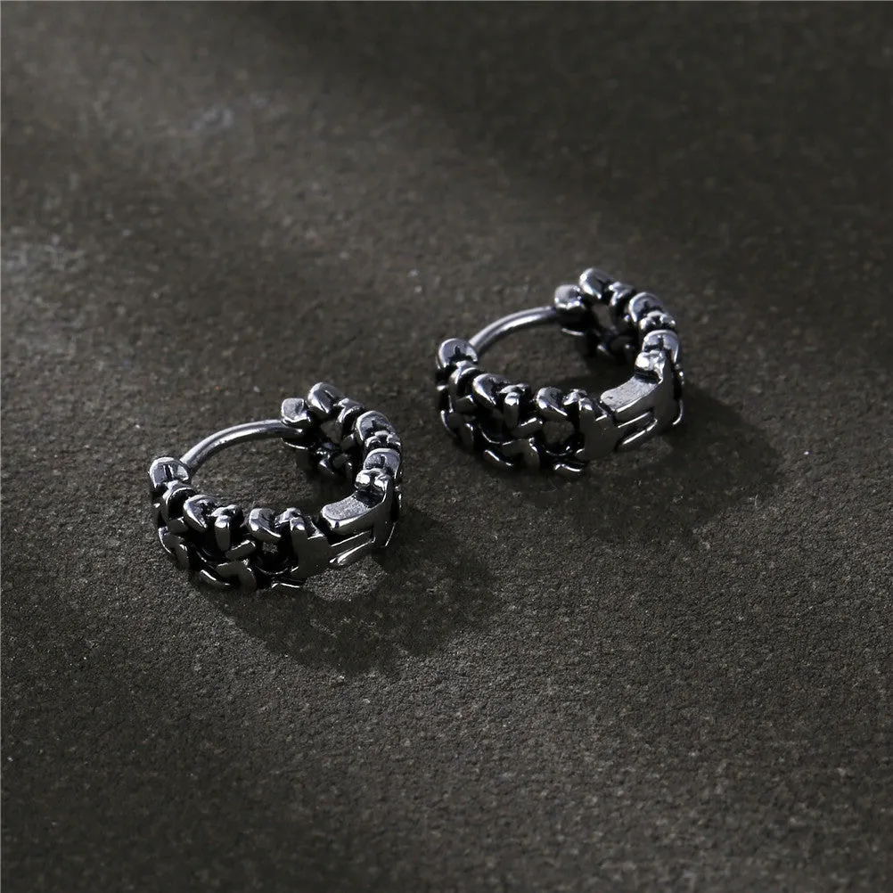 Close-up of a pair of men's geometric copper hip hop earrings on a dark background.