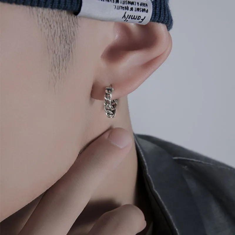 Close-up of a pair of men's geometric copper hip hop earrings on a dark background.