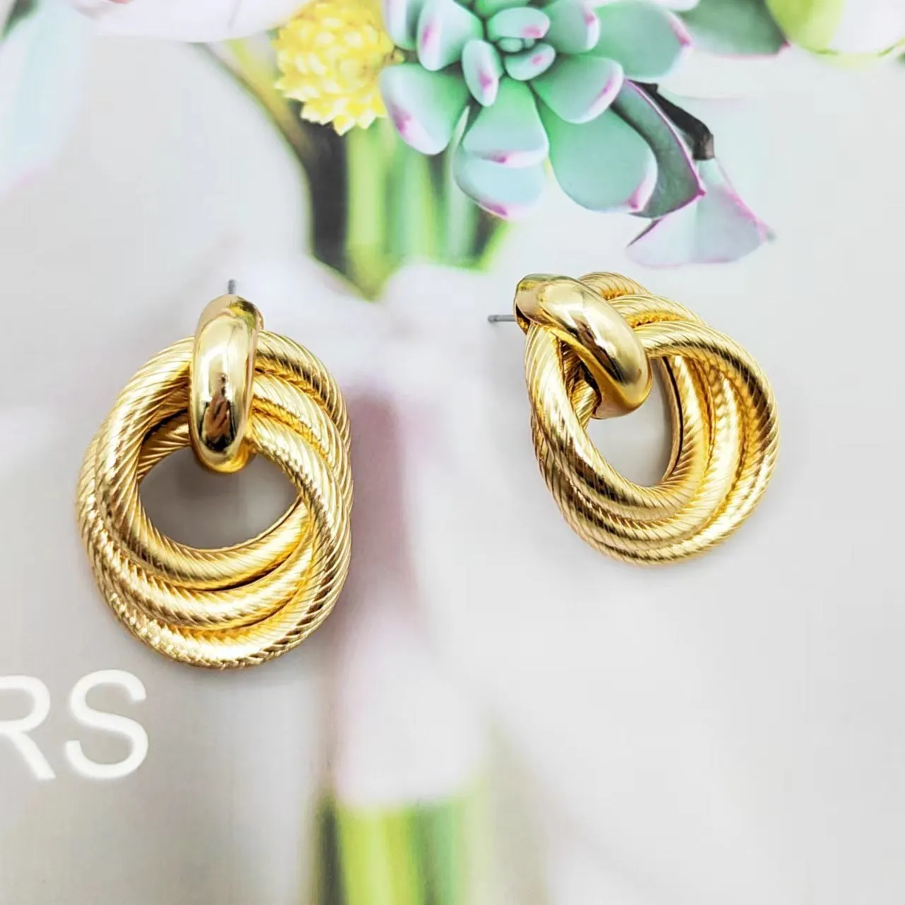 Gold geometric ring embossed twisted stud earrings on white background