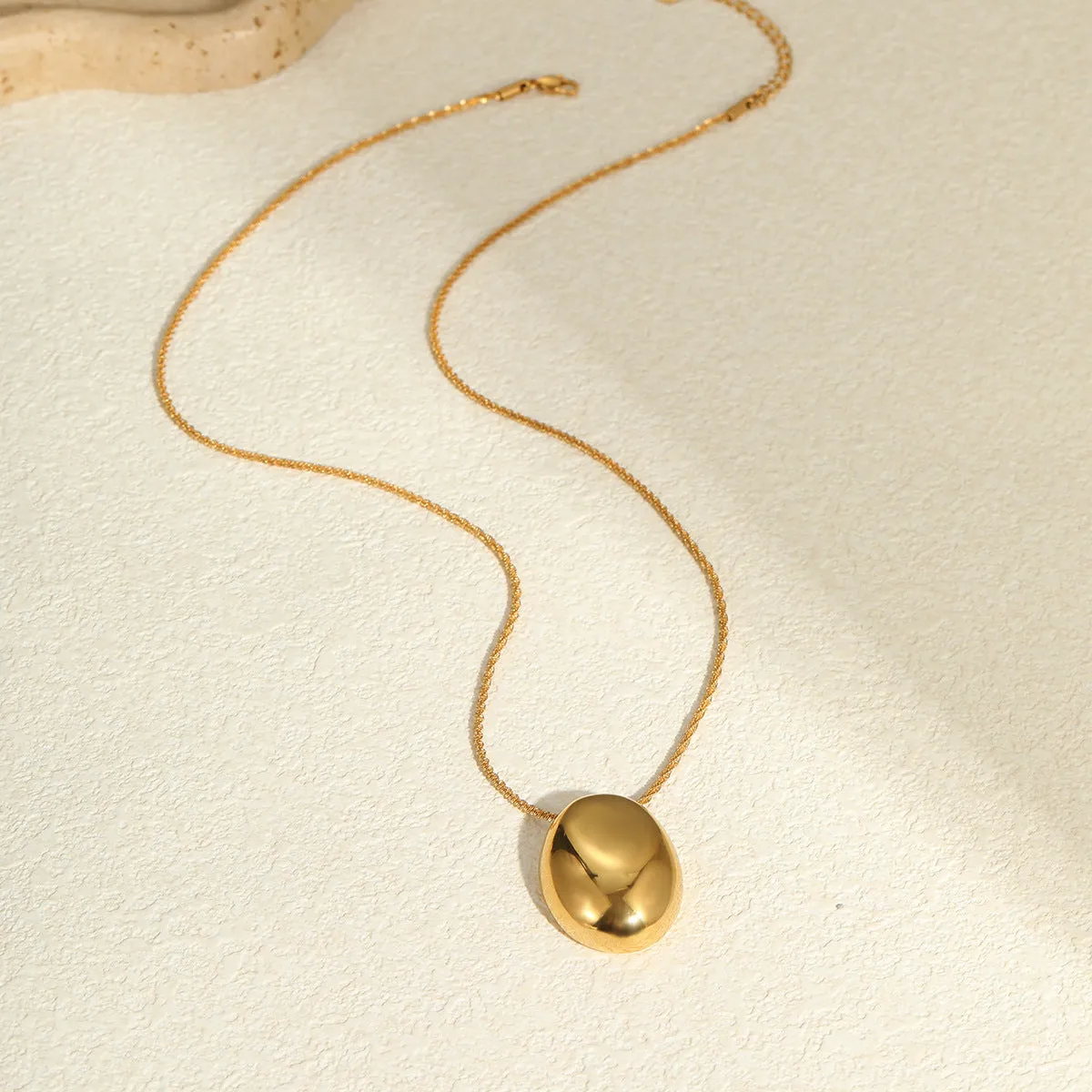Gold geometric pendant necklace with adjustable chain on plain background