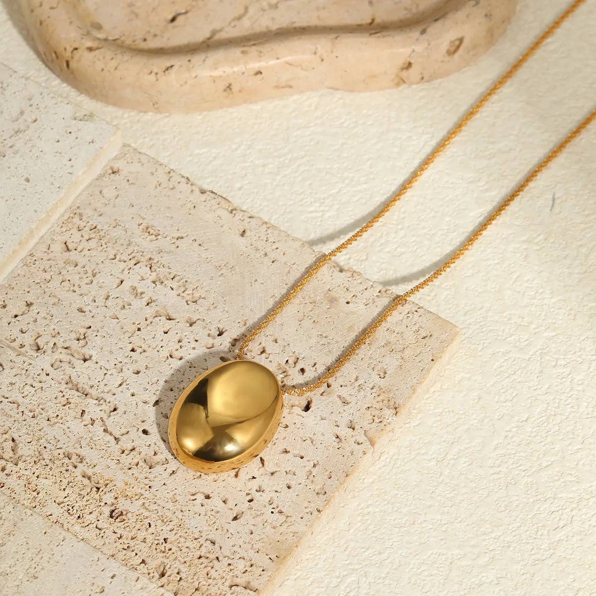 Gold geometric pendant necklace with adjustable chain on plain background