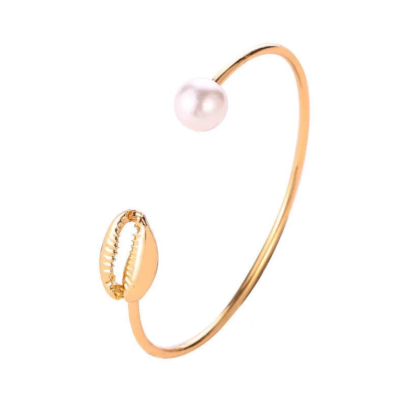Alloy opening bracelet with pearl and shell decoration in gold finish on white background