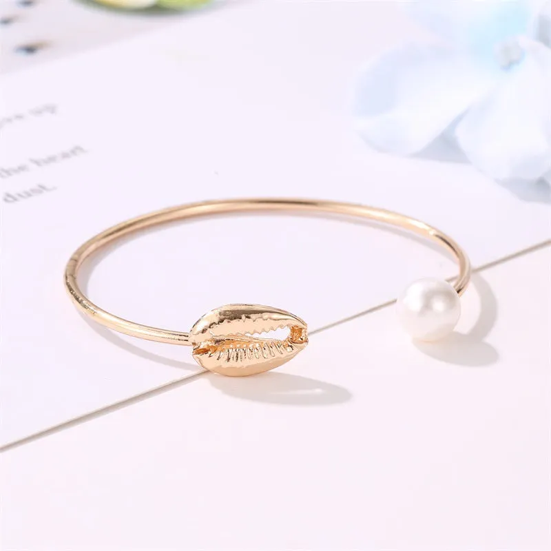 Alloy opening bracelet with pearl and shell decoration in gold finish on white background