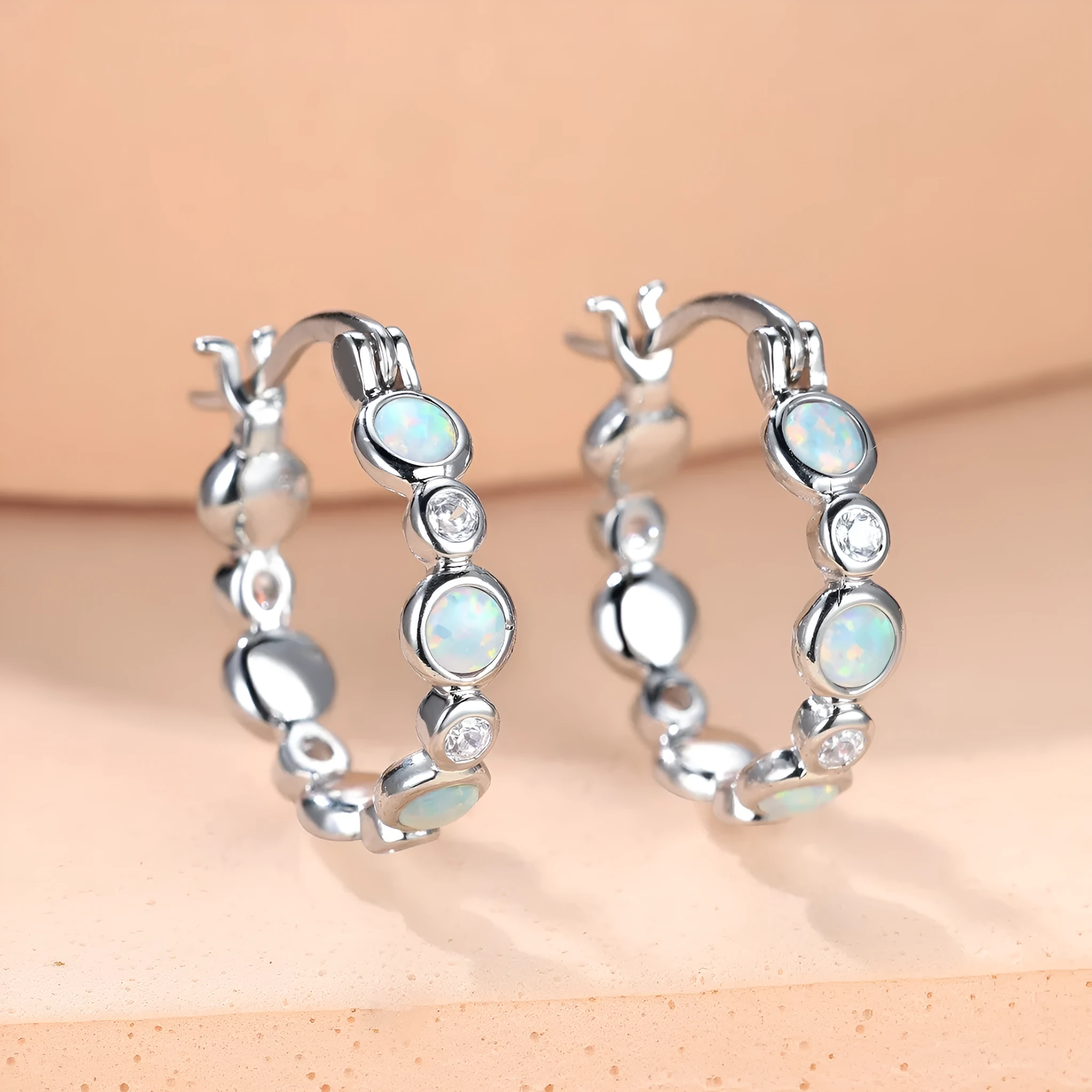 Round copper earrings with synthetic opal and cubic zirconia in platinum white finish
