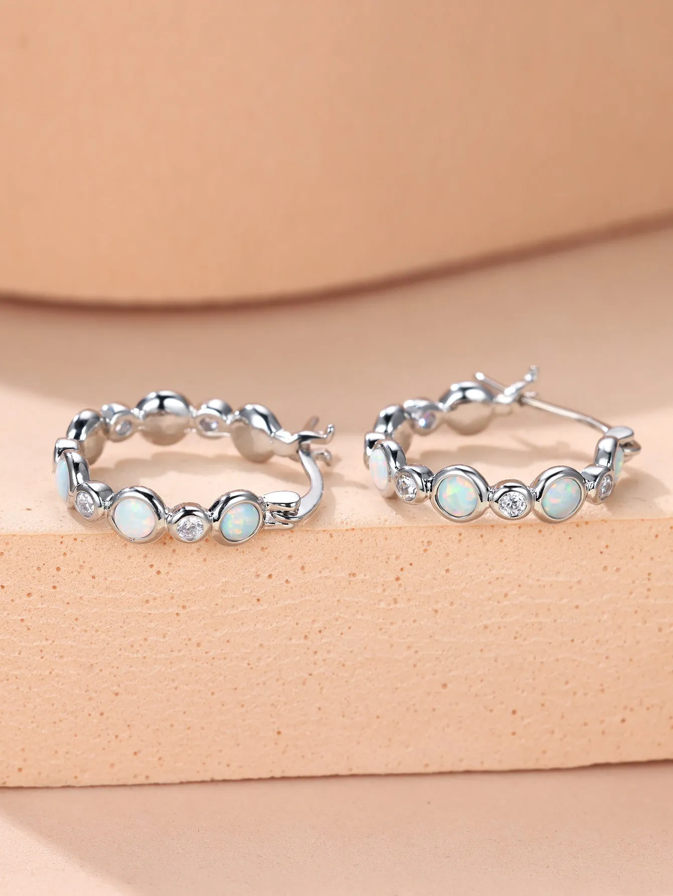Round copper earrings with synthetic opal and cubic zirconia in platinum white finish