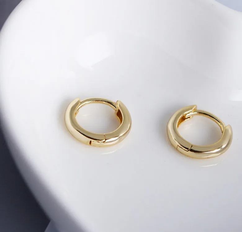 Women's sterling silver round stud earrings in gold colour, 1cm diameter, on a white surface