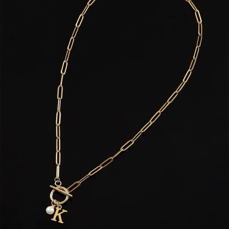 Stainless steel clip chain necklace with raised letter A pendant and imitation pearl in gold colour on a white background