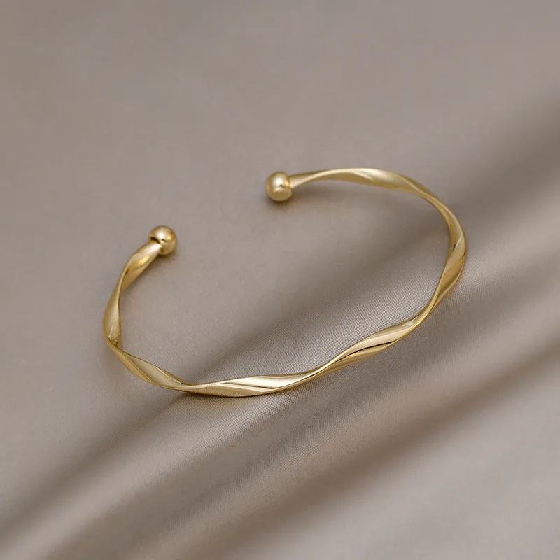 Gold alloy geometric twist bracelet with 6.2 cm inner ring diameter on white background