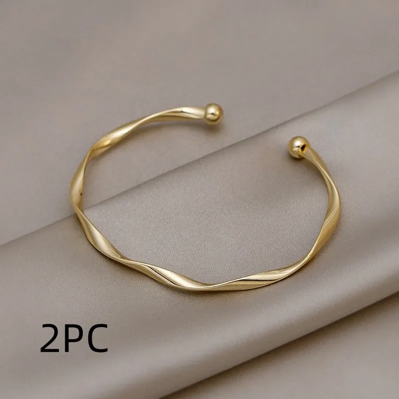 Gold alloy geometric twist bracelet with 6.2 cm inner ring diameter on white background