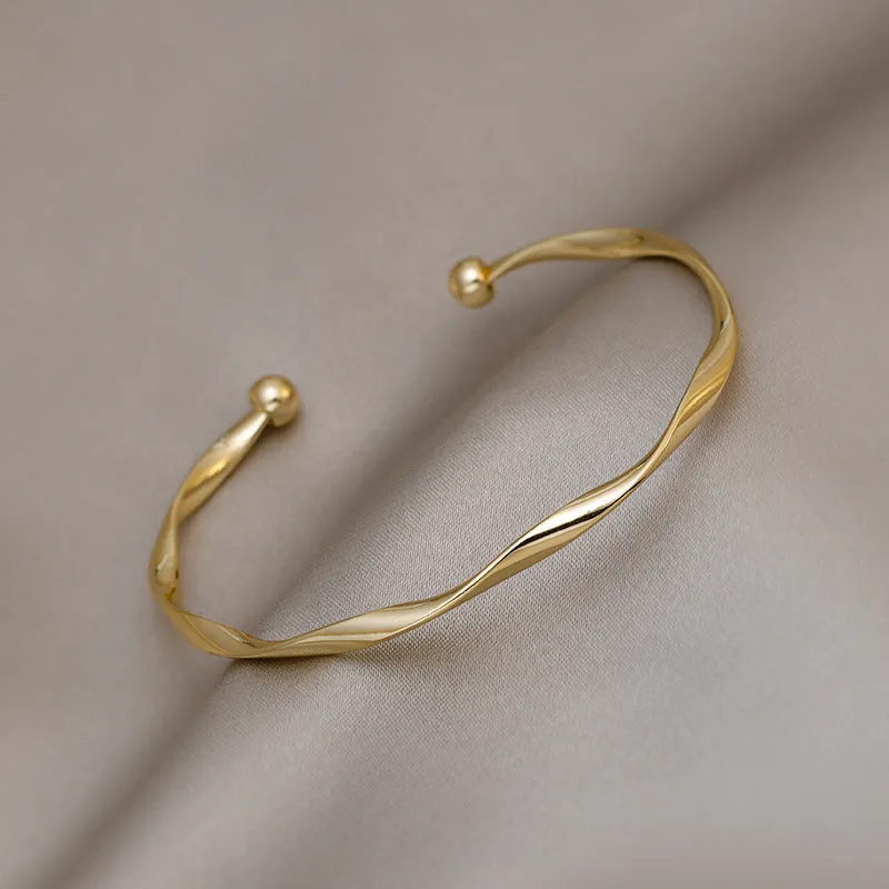 Gold alloy geometric twist bracelet with 6.2 cm inner ring diameter on white background