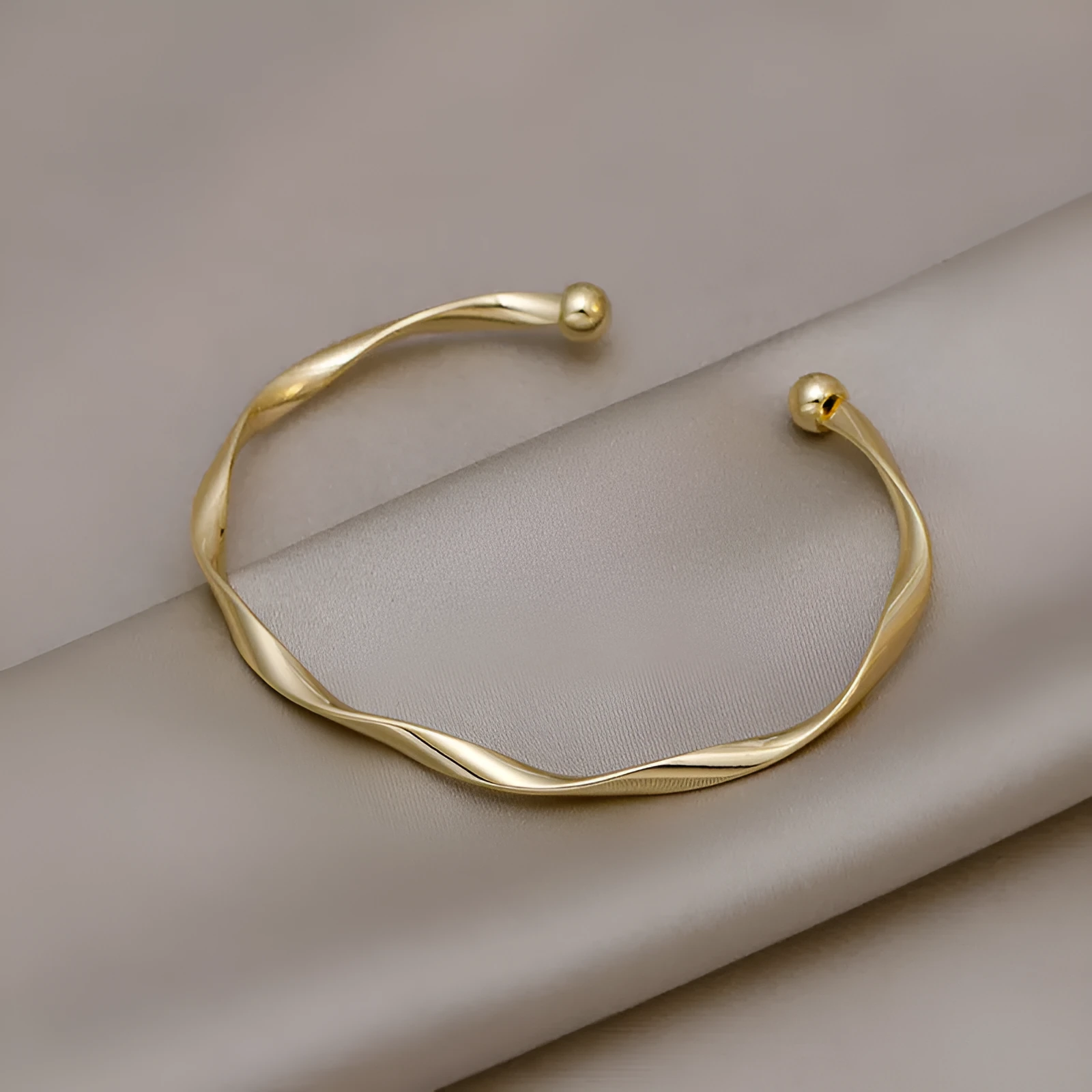Gold alloy geometric twist bracelet with 6.2 cm inner ring diameter on white background