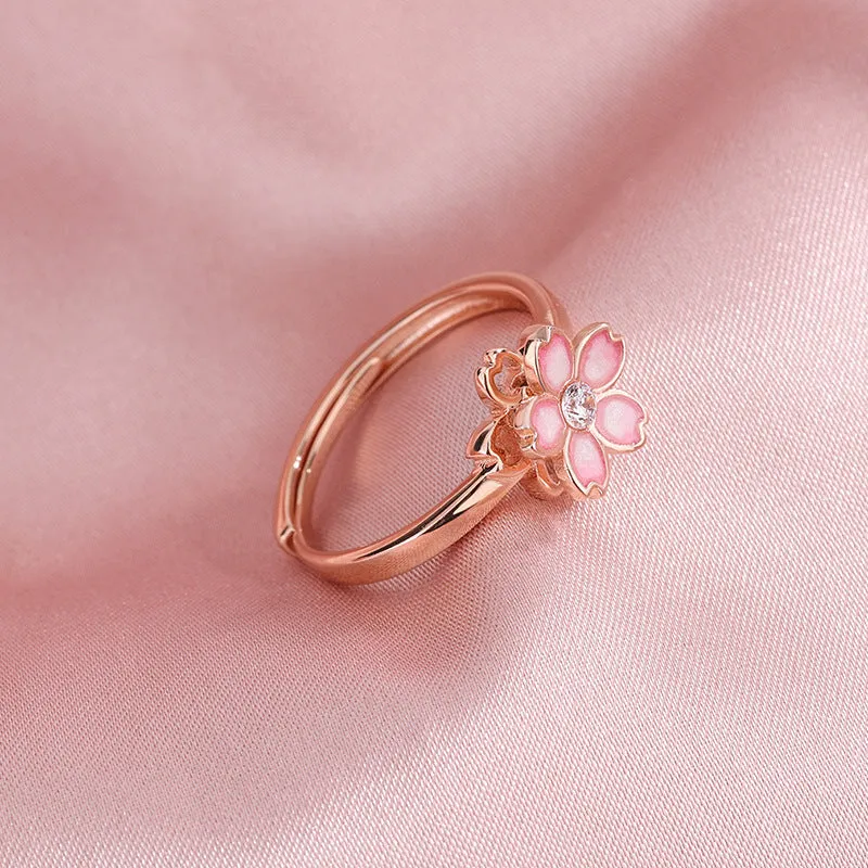 Cherry blossom rotatable ring with rose gold finish, adjustable opening, and silver base shown on a finger