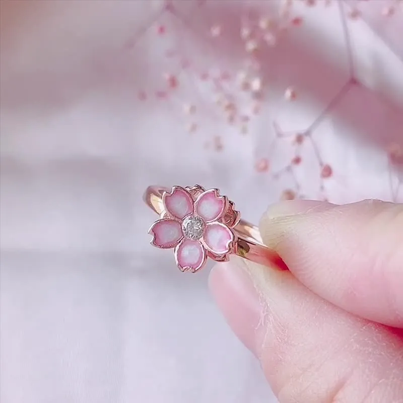 Cherry blossom rotatable ring with rose gold finish, adjustable opening, and silver base shown on a finger