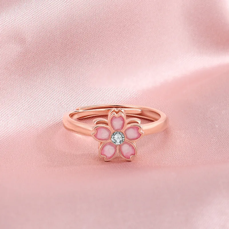 Cherry blossom rotatable ring with rose gold finish, adjustable opening, and silver base shown on a finger