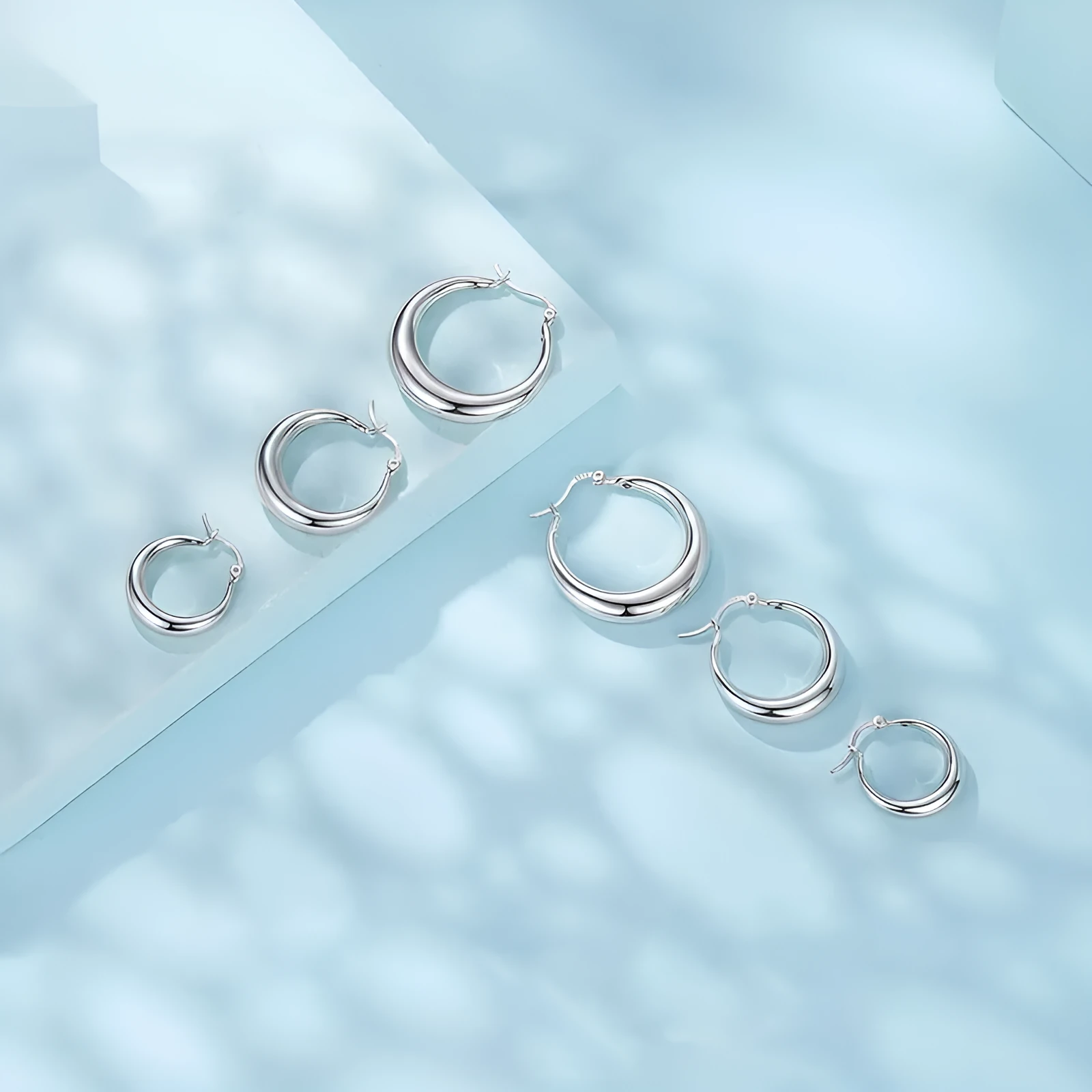 A pair of copper geometric ring ear clips with a silver needle, shown in large, medium, and small sizes.