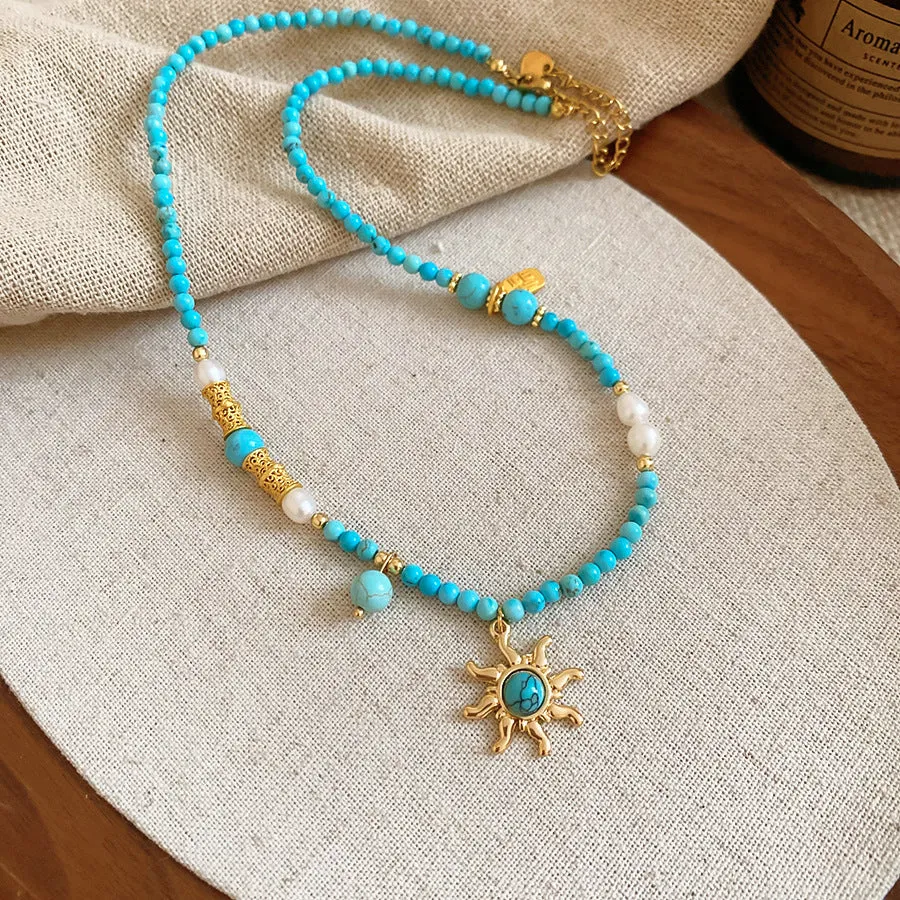 Freshwater pearl necklace with a blue stone sun pendant on an adjustable gold-toned chain.