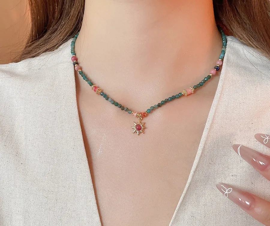 Freshwater pearl necklace with a blue stone sun pendant on an adjustable gold-toned chain.