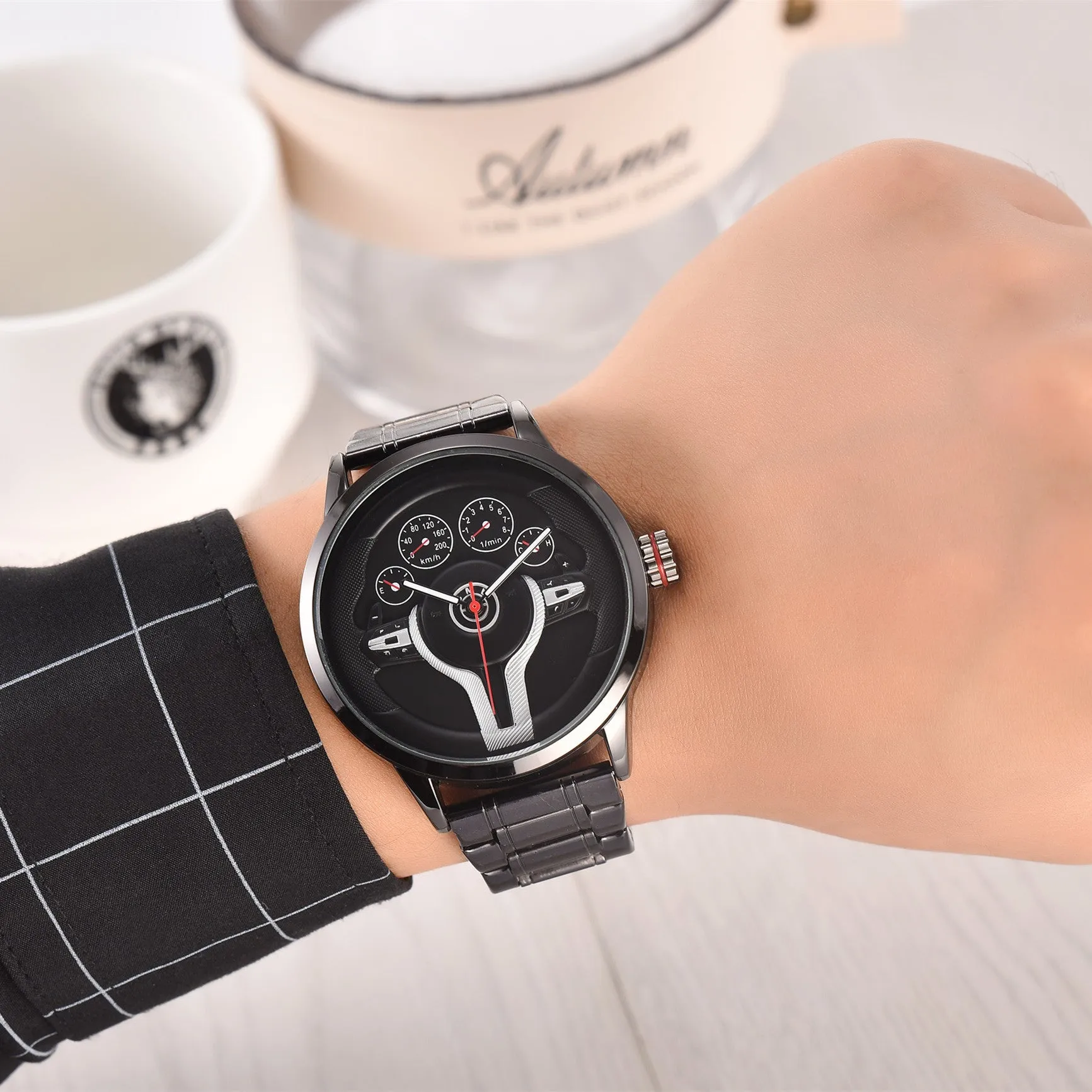 Steering wheel fashion watch with 43mm circular alloy case, stainless steel strap, and pointer display on a light background.