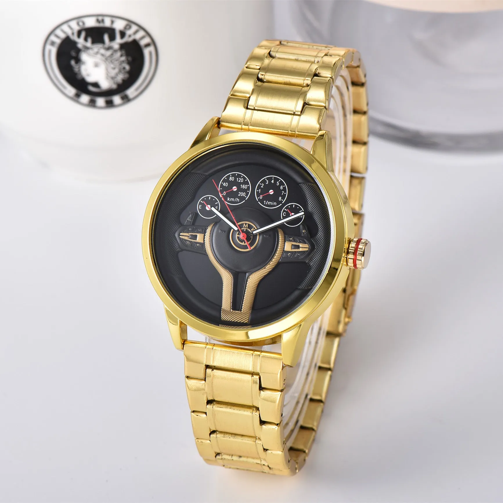 Steering wheel fashion watch with 43mm circular alloy case, stainless steel strap, and pointer display on a light background.