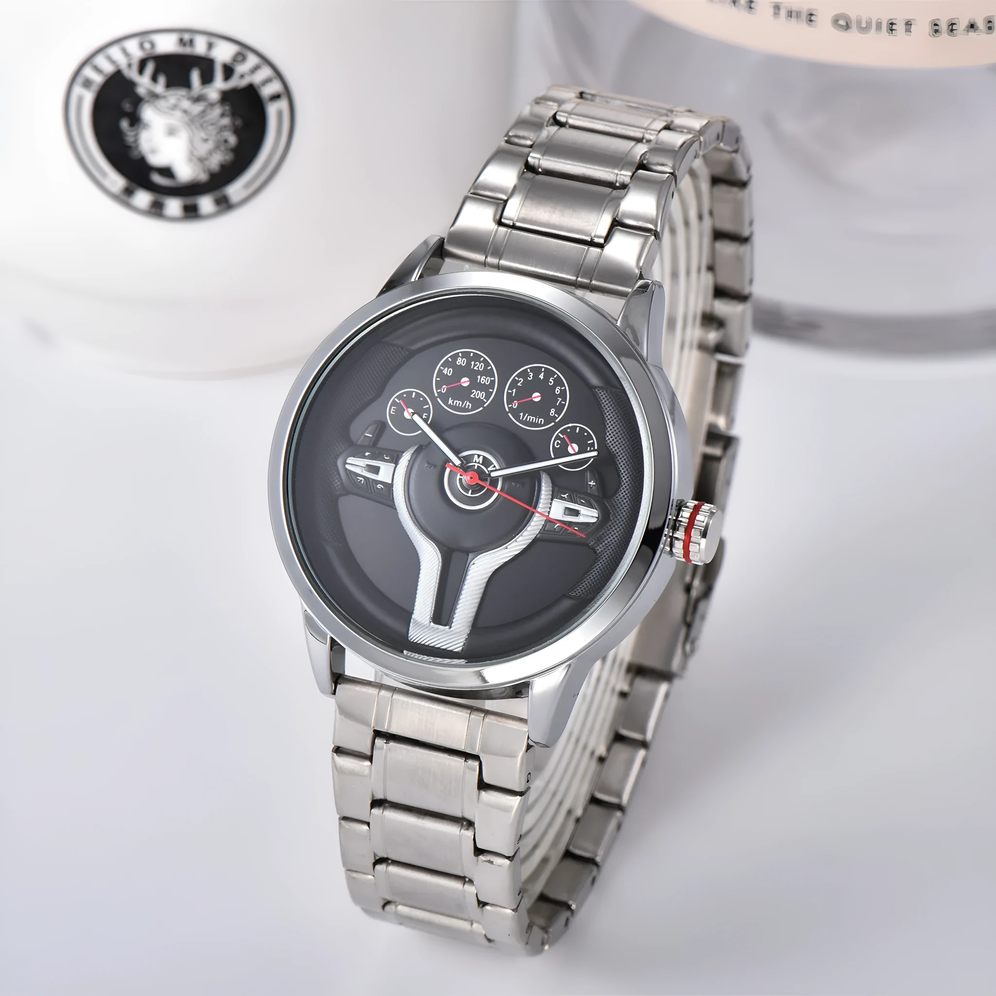 Steering wheel fashion watch with 43mm circular alloy case, stainless steel strap, and pointer display on a light background.