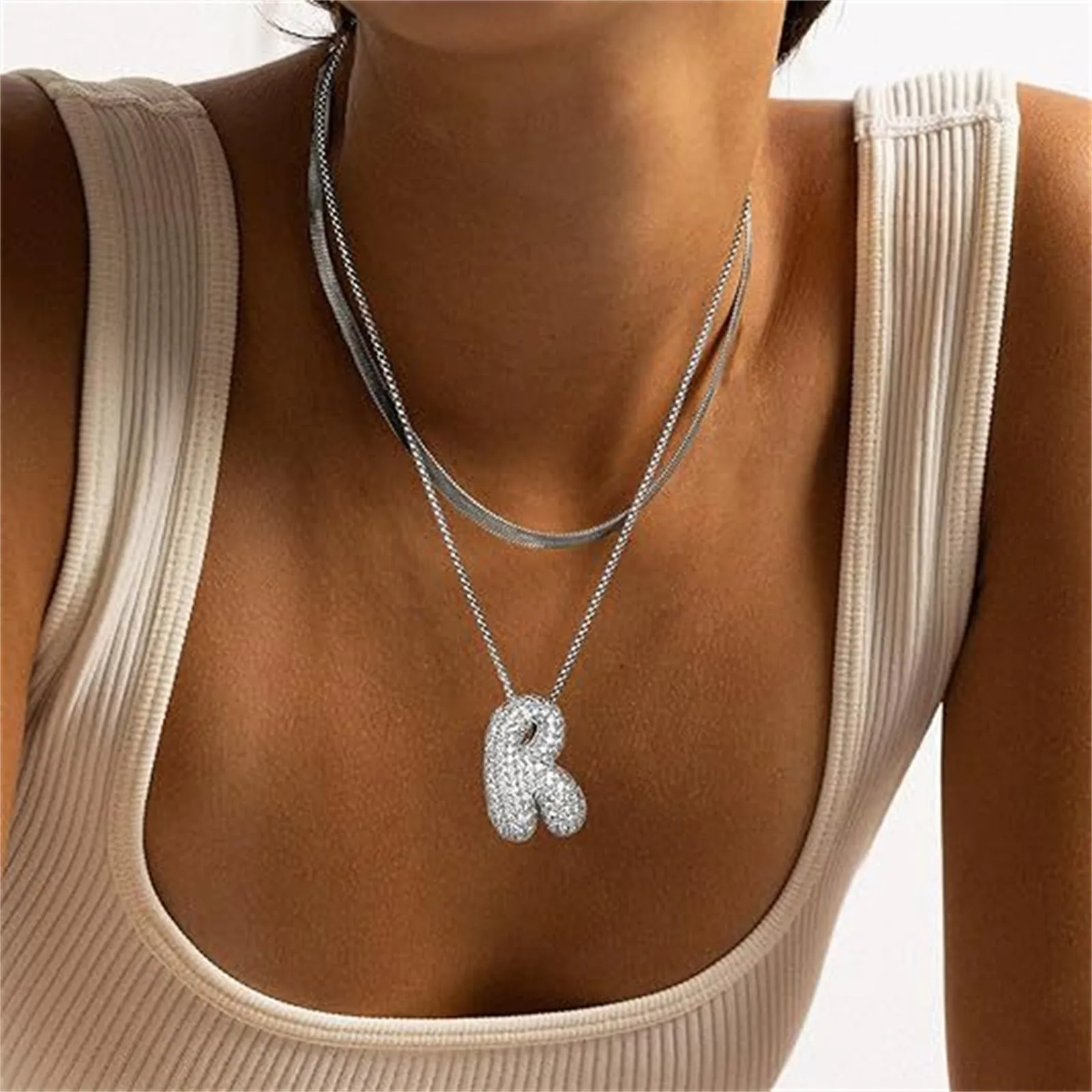 Brass zircon balloon English letter necklace in gold finish, copper base with inlaid zircon stones, on a woman's collarbone