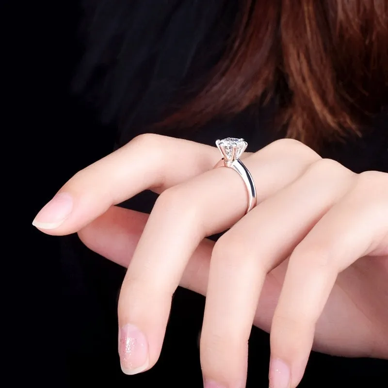 White gold plated six-claw zircon ring with a geometric design on a finger.